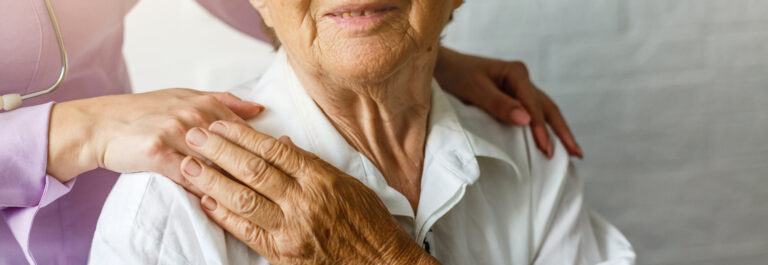 Elderly female hand holding hand of young caregiver at nursing h