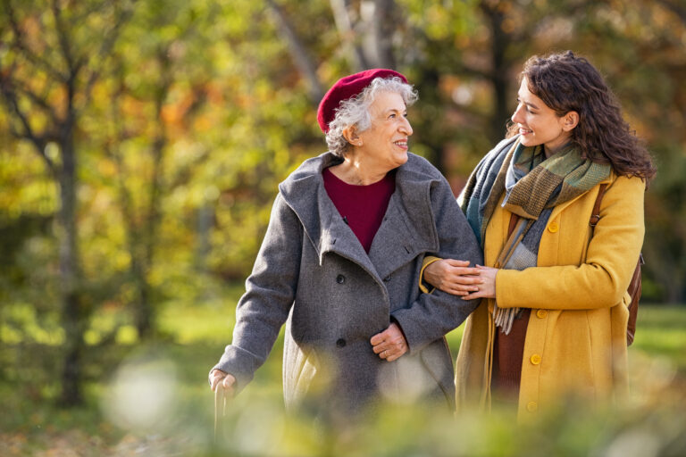 Senior woman walking with granddaughter in park during autumn